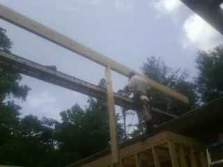Carpenter setting a ridge beam over a new addition frame — Ice Dam Removal by Roofing Brothers in Tobias