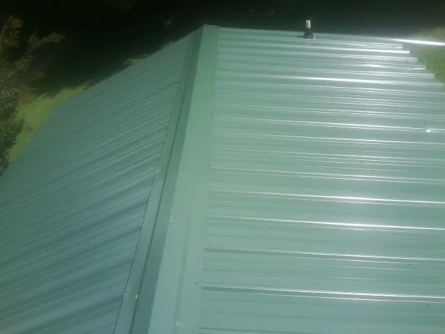 New green metal panels meeting at the ridge of a roof — Flat Roof Repair work by our crew in Tobias