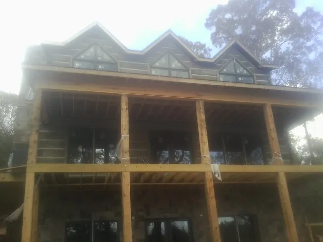 Dormers and porch framing on a large log home under construction — Roof Coating work by our crew in Tobias