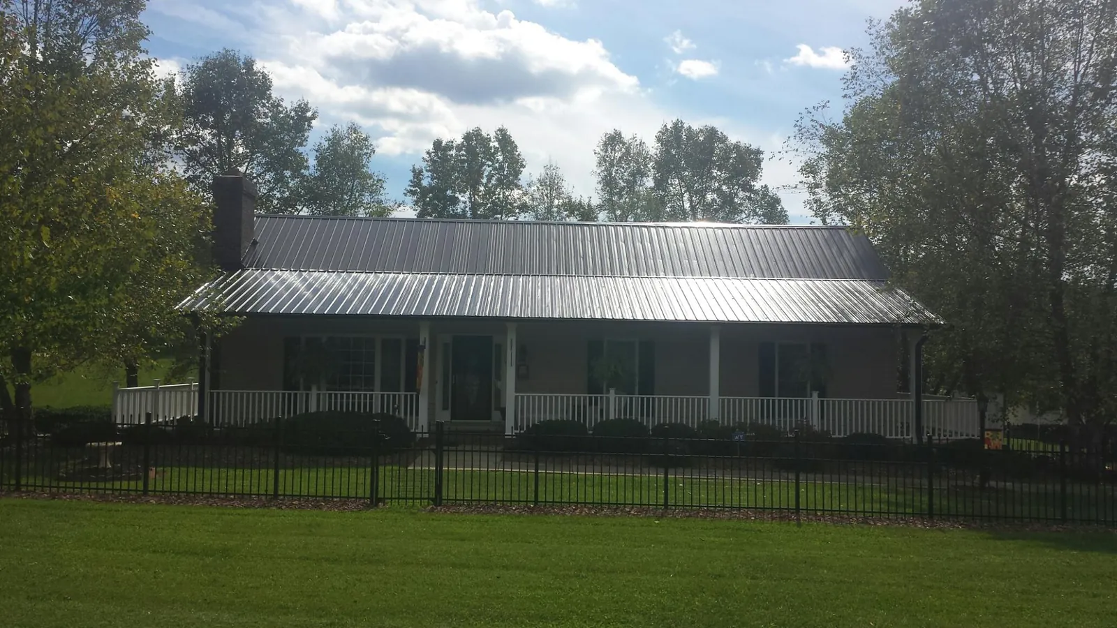 Gray metal roof on a brick ranch with a full width front porch — Gutter Guard Installation work by our crew in Tobias