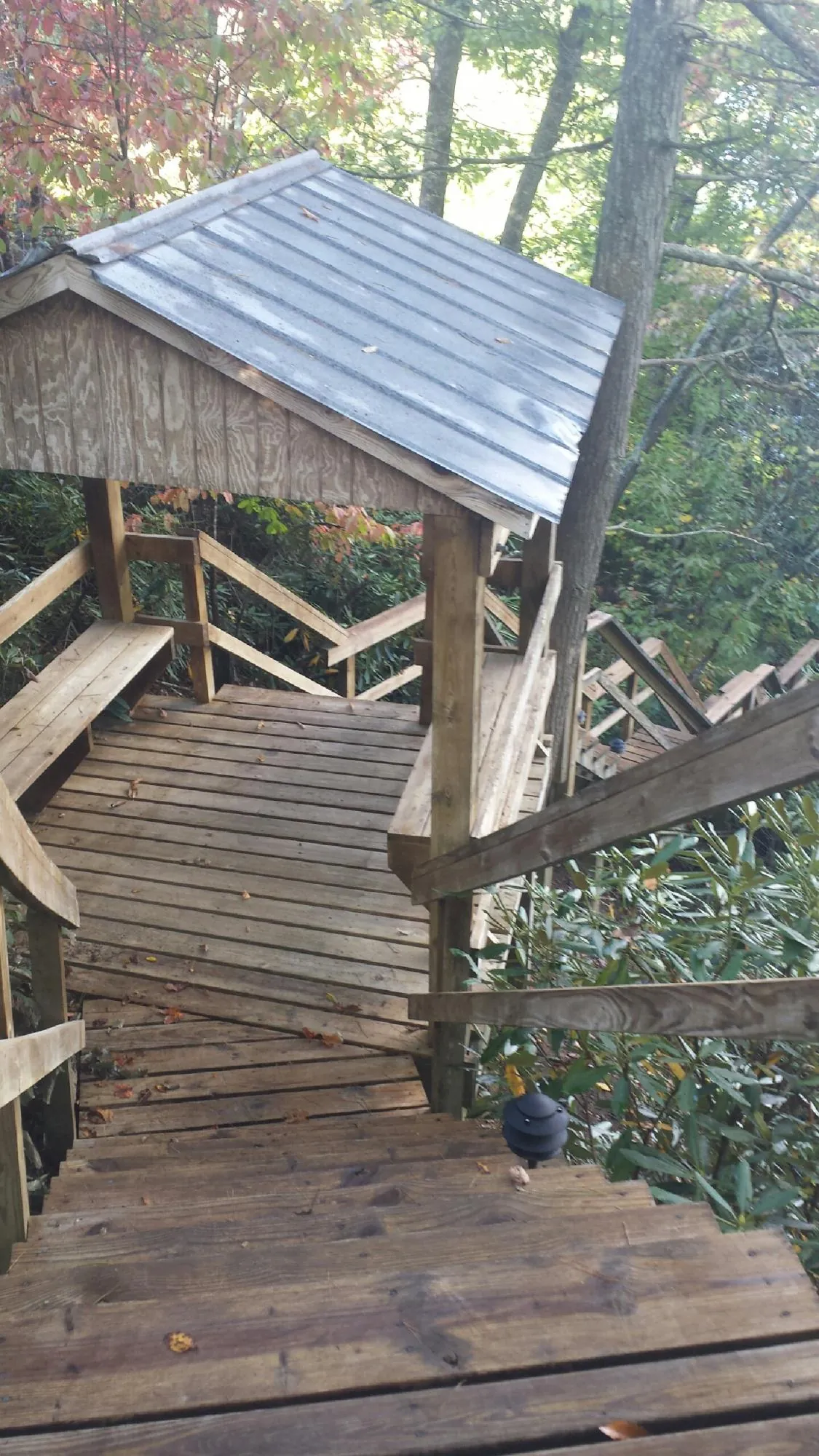 Metal roofed shelter over wooden steps on a wooded walkway — Skylight Repair & Installation work by our crew in Tobias