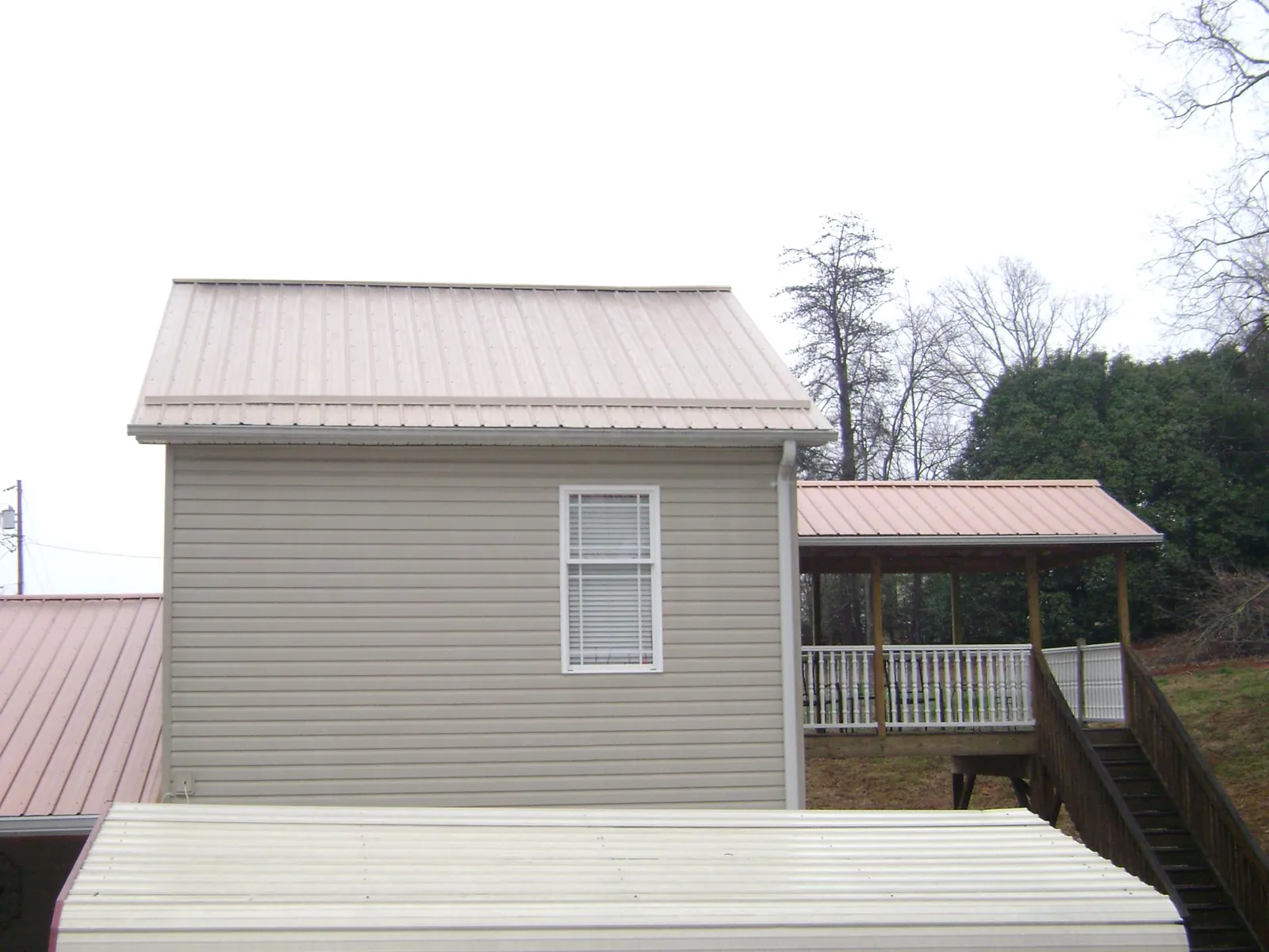 Tan metal roofs on a two story addition and attached porch, from a Roof Replacement job in Tobias