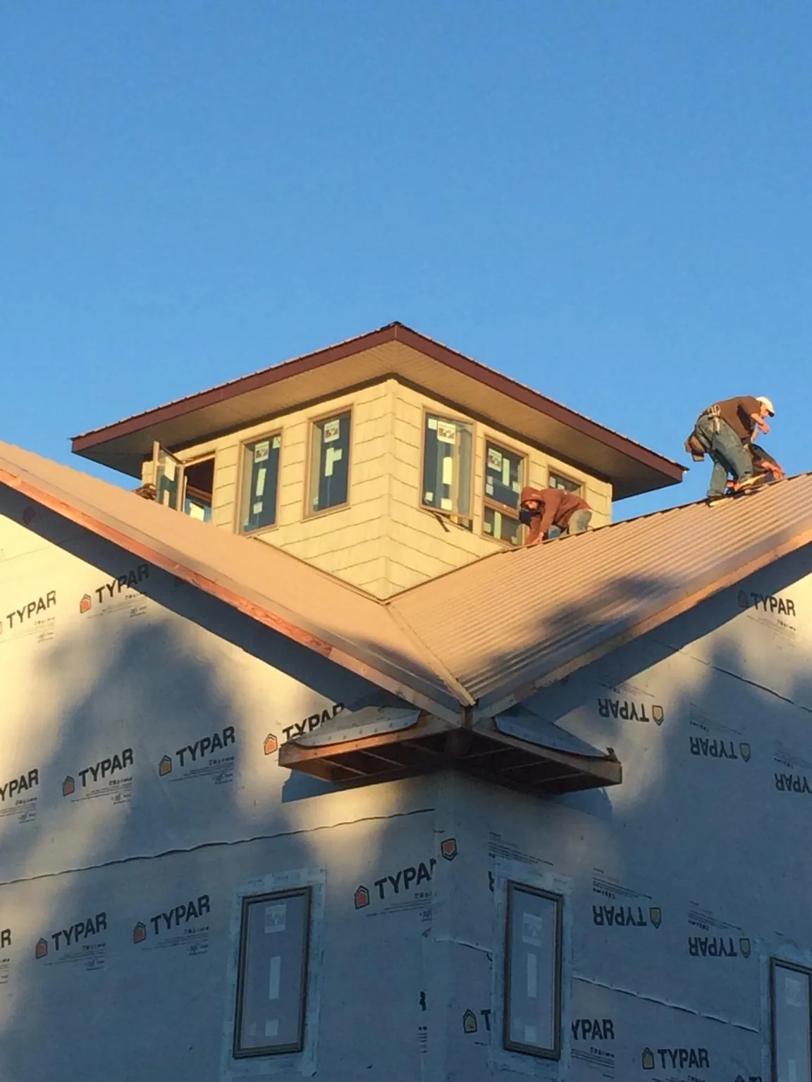 Roofers working around a rooftop cupola on a new metal roof at sunset — Roof Waterproofing in Tobias by Roofing Brothers